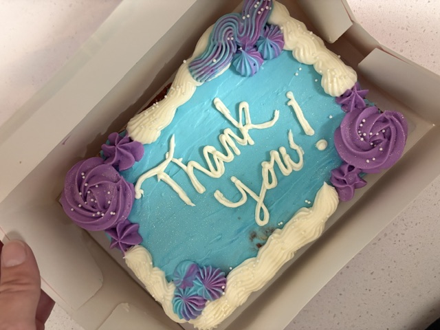 Close-up of a custom Thank You cookie cake with teal and purple buttercream